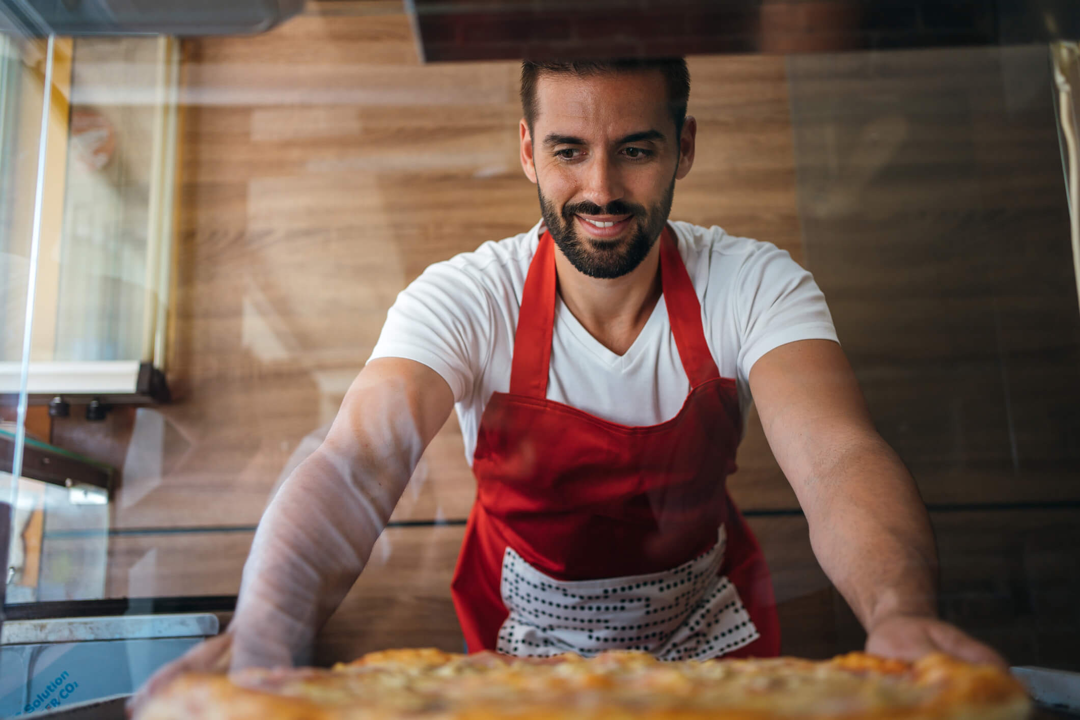 pizza maker putting pizza in display case