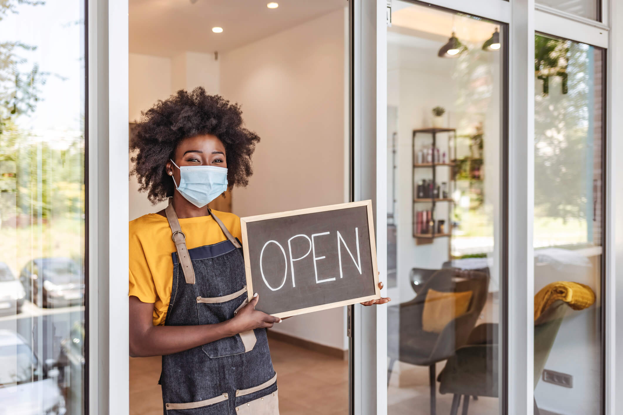 Girl With a Mask On Holding an Open Sign Storefront